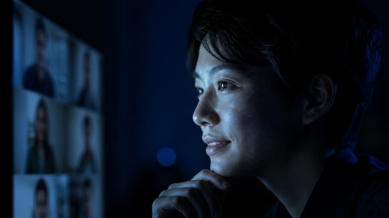 Presenter on a video call lit by screen light during a live stream swap session
